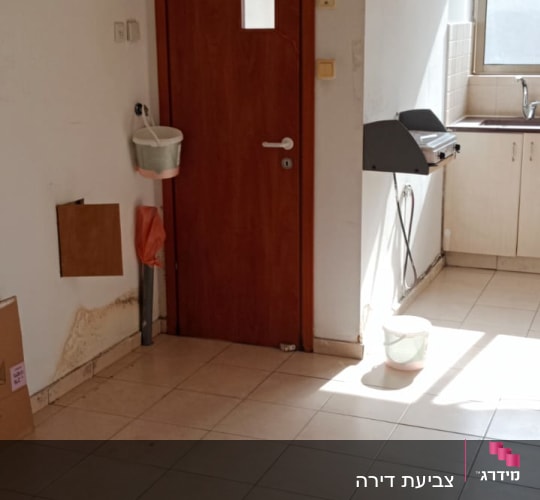קיר גבס עם סימני רטיבות ליד דלת עץ